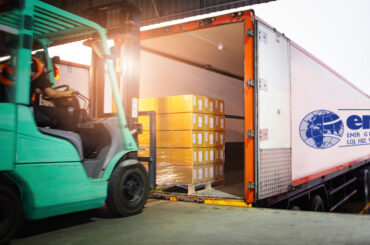 Forklift Tractor Loading Package Boxes on Pallet into Cargo Container. TrailerTruck Parked Loading at Dock Warehouse. Shipment Delivery. Supply Chain. Shipping Logistics Freight Truck Transportation.